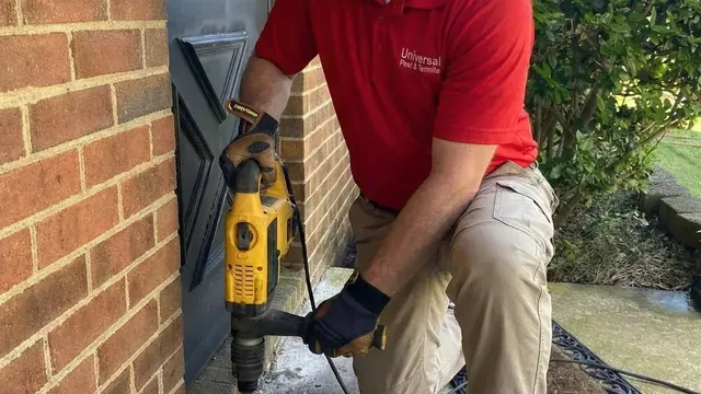 Technician applying liquid termiticide into a trench along a residential foundation during termite treatment in Virginia Beach.