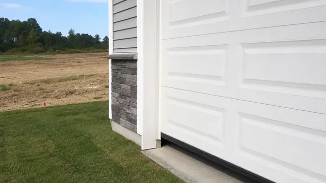 The garage door of a newly built home sitting slightly proud of its concrete apron, leaving a shadowed gap along the bottom edge.