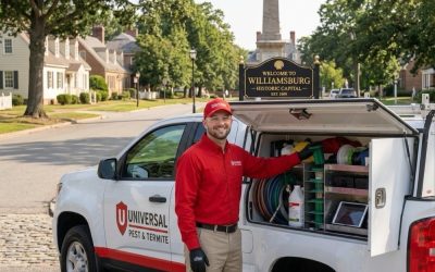 "Professional termite technician from Universal Pest & Termite standing with a service truck in historic Williamsburg, VA, showing the Sentricon termite baiting system and equipment ready for home inspections near Colonial Williamsburg